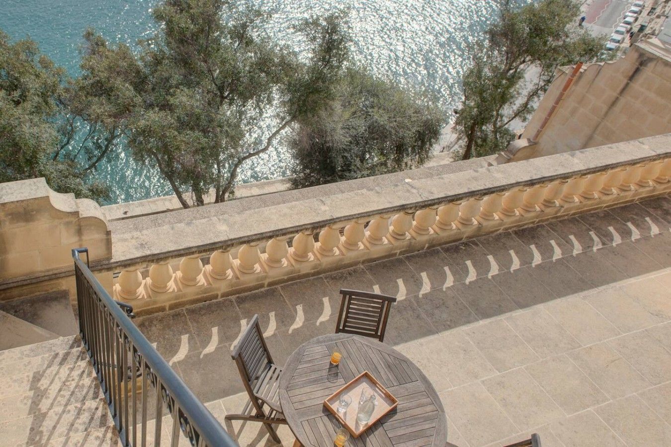 A terrace with a table and chairs, overlooking a body of water and trees.
