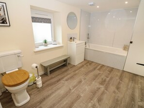 A modern bathroom with a toilet, sink, bench, and shower. - Gap Farm (Brampton)