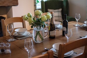 A dining table set with plates, glasses, a bottle of wine, a pitcher of water, and a vase with flowers. - Gap Farm (Brampton)
