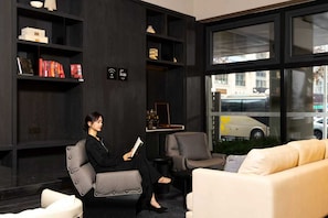 Un interior moderno con un sofá, sillones y una estantería.