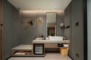 Un baño moderno con un espejo grande, un lavamanos y un pequeño espacio de almacenamiento.