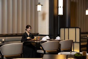 Un comedor con una persona sentada a la mesa, rodeado de sillas y una decoración de diseño moderno.
