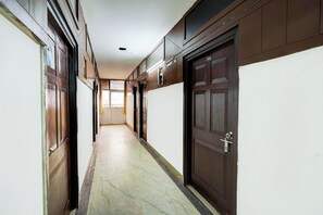 Un pasillo con puertas a ambos lados, suelo de baldosas e iluminación empotrada en el techo.