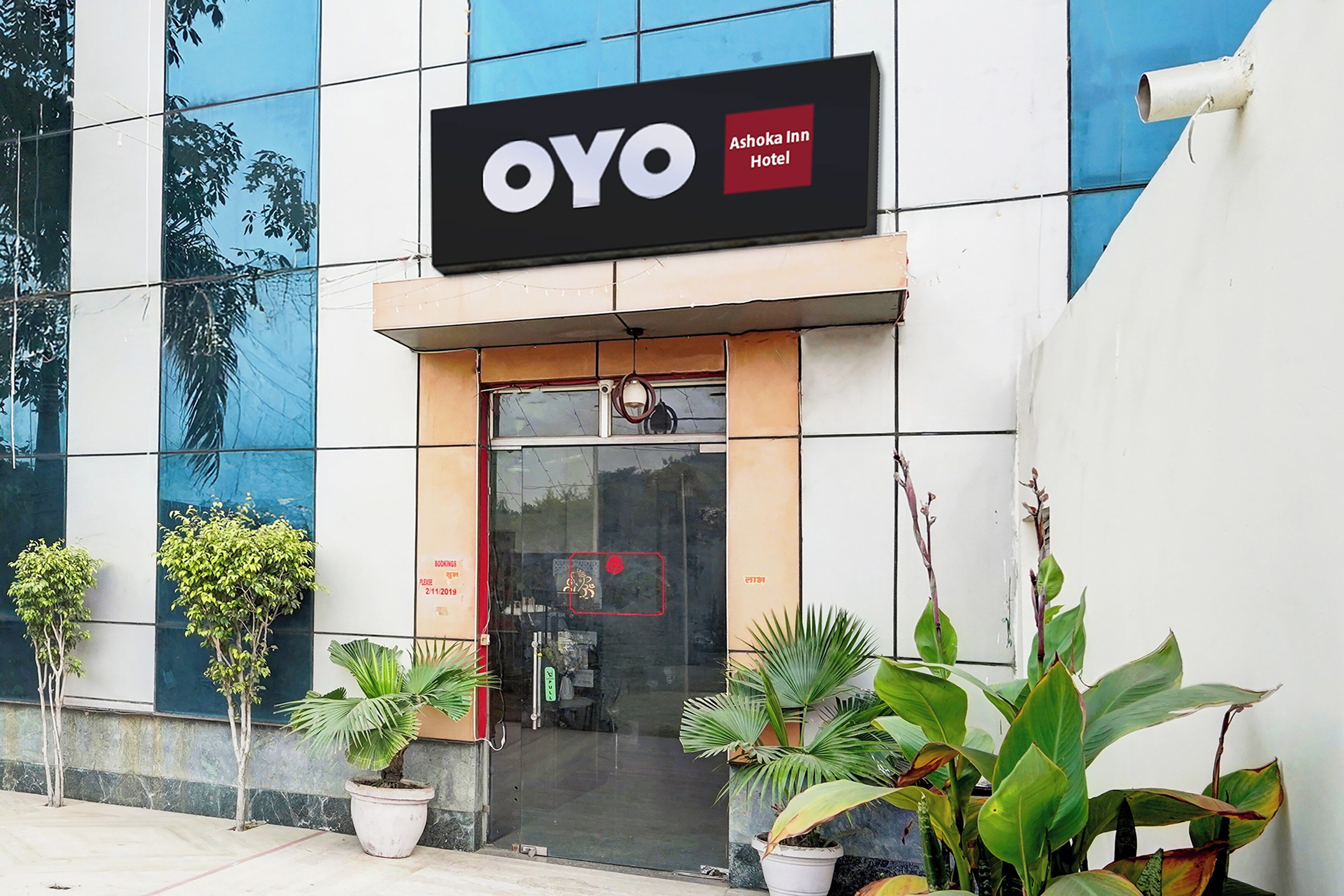 L’extérieur de l’hôtel OYO Ashoka Inn se distingue par sa façade moderne, une enseigne bien visible et des plantes en pot placées devant l’entrée.
