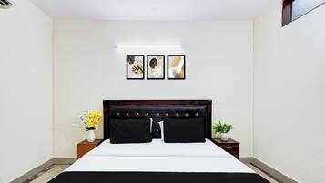 Een slaapkamer met een bed, nachtkastjes, een wandairconditioner en kunstwerken in lijsten.