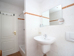 A bathroom with a white sink, a mirror, and a shower. - Villa Mowe Holiday Apartment D (Sylt)
