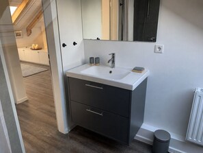 A modern bathroom with a white sink, dark cabinetry, and a mirror above. - Holiday Apartment With 1 Bedroom (Gluecksburg)