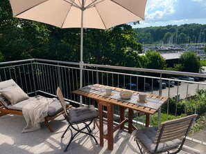 A balcony with a table, chairs, and an umbrella. - Holiday Apartment With 1 Bedroom (Gluecksburg)