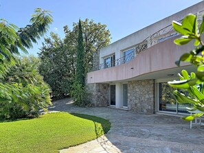 A modern house with a stone facade, large windows, and a well-maintained garden. - Beautiful villa, ocean view, pool, beach within walking distance (Corbara)