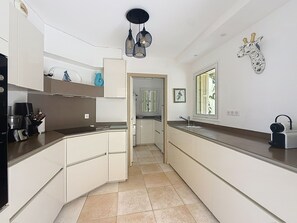 A modern kitchen with white cabinetry, a black countertop, and a hanging light fixture. - Beautiful villa, ocean view, pool, beach within walking distance (Corbara)