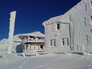 Ein mit Schnee bedecktes Gebäude mit Balkon und Schornstein.