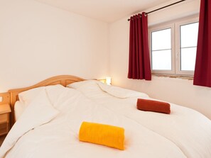 Ein Hotelzimmer mit einem Bett, einem Nachttisch, einem Fenster mit Vorhängen und einer Lampe.
