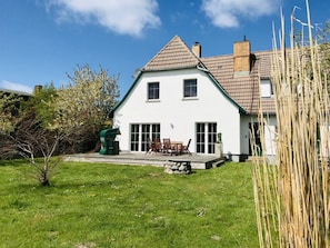 A two-story house with a tiled roof, a front porch with chairs, and a small garden area. - Treasure Island Prerow (Ostseebad Prerow)