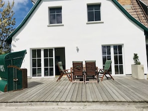 A white building with a wooden deck, two windows, and a door. - Treasure Island Prerow (Ostseebad Prerow)
