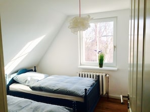 A bedroom with a bed, a window with a plant, and a radiator. - Treasure Island Prerow (Ostseebad Prerow)