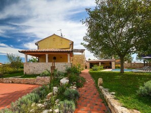 A two-story house with a stone facade, a tiled roof, and a small garden with a pathway leading to a pool. - Villa Orbanici With Pool (Marcana)