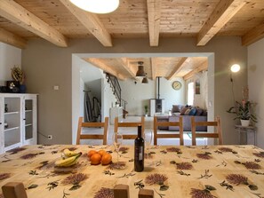 A dining area with a wooden table set for two, a bottle of wine, and fruit. - Villa Orbanici With Pool (Marcana)