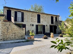 A stone building with a courtyard, featuring a central door, windows, and potted plants. - Holiday Apartment With 2 Bedrooms (Massa Marittima)