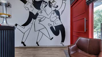 Una stanza con una porta rossa, una poltrona in pelle marrone e un affresco sulla parete.