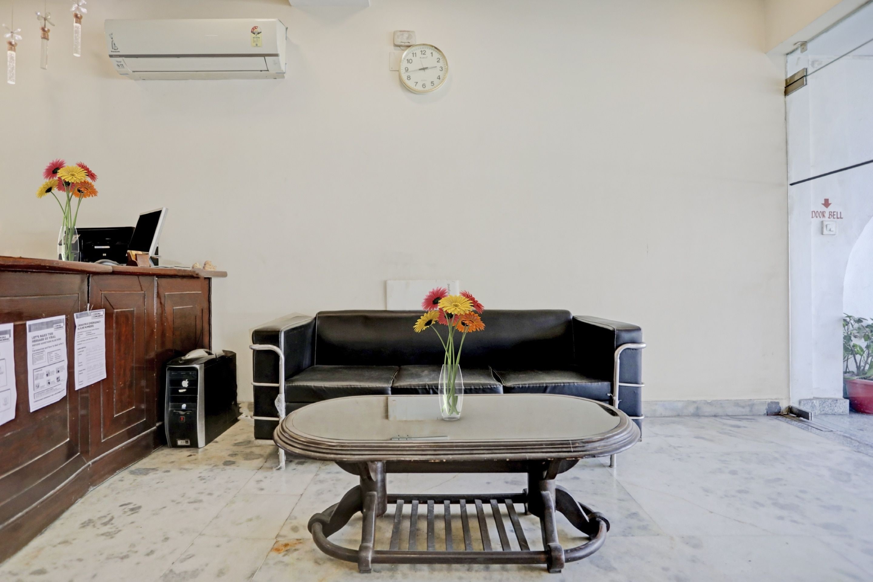 Un área de recepción con mostrador, reloj, sofá y mesa de centro.