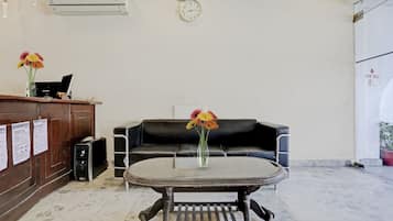 Un área de recepción con mostrador, reloj, sofá y mesa de centro.