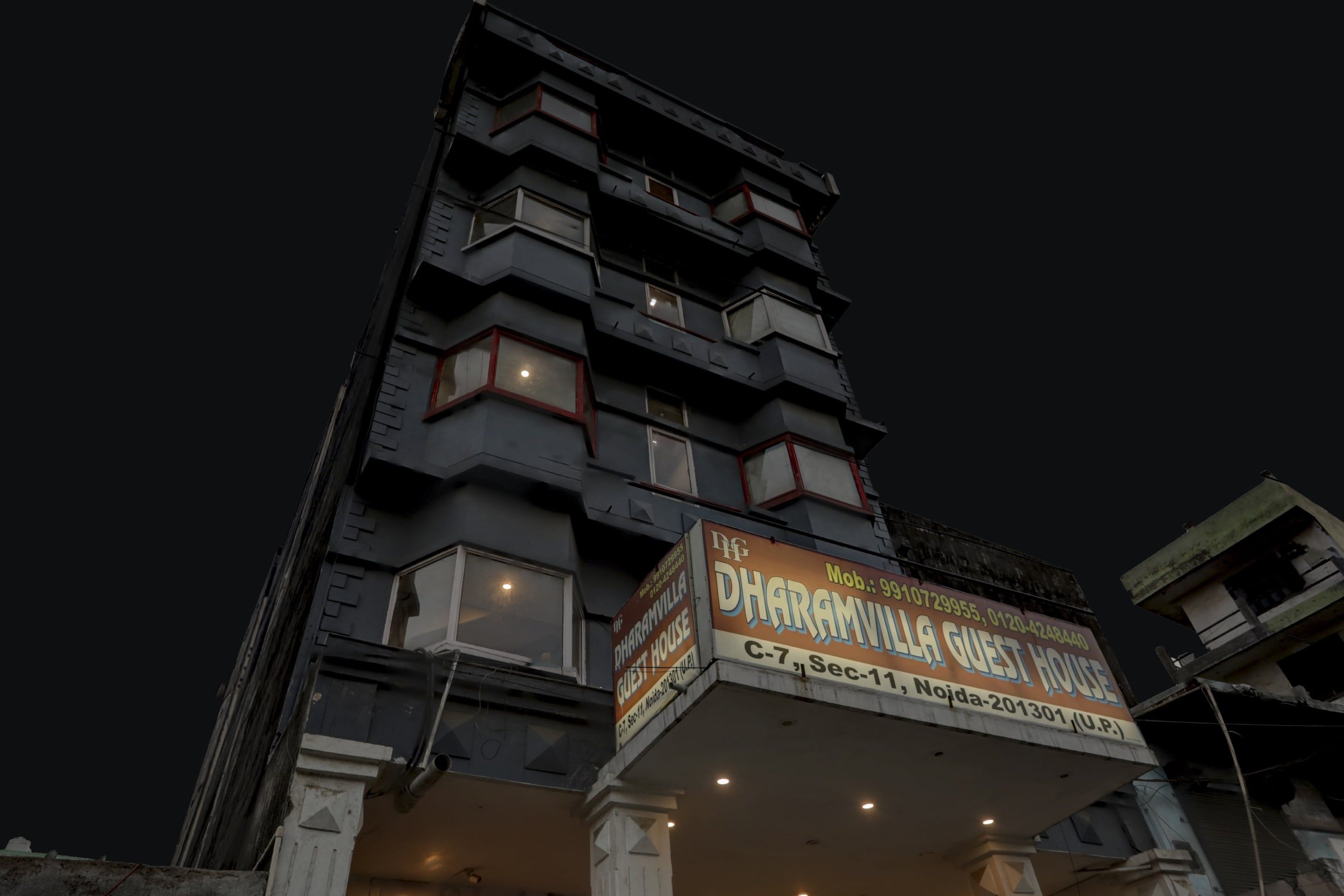 A multi-story building with a sign for 'Dharamvil Guest House' at the ground level.