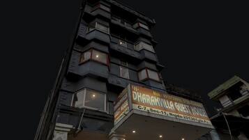 Un edificio de varios pisos con un letrero que indica 'Dharamvil Guest House' al nivel de la calle.