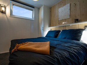 Ein Schlafzimmer mit einem Bett, einem Fenster und einer Holzwand.