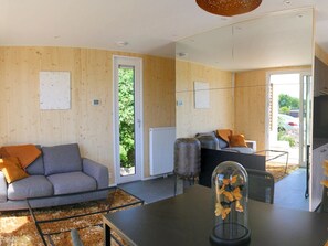 Ein modernes Wohnzimmer mit einem grauen Sofa, einem Couchtisch und einer Vitrine mit Blättern.