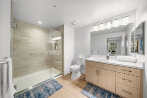 Une salle de bain moderne avec une douche à parois de verre, des toilettes, un lavabo avec un miroir et des meubles en bois.