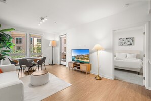 Un salon moderne doté d’un téléviseur à écran plat, d’un coin repas et d’une chambre à coucher avec un lit.