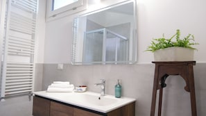A bathroom with a white sink, a mirror, a towel rack, a plant, and a wooden stool. - La Casa del Pittore: a detached house with a large garden in Pecetto Torinese (Pecetto Torinese)