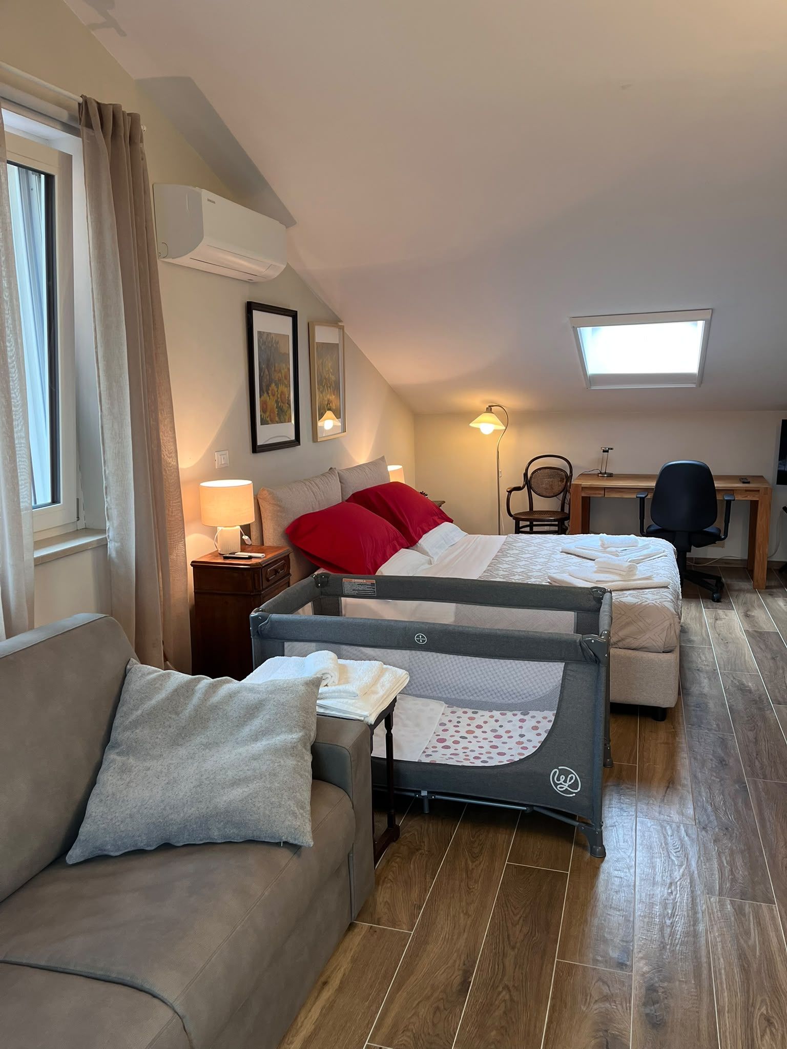 A compact room with a bed, a sofa, a desk, and a chair.