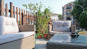 A patio area with wicker furniture, including two sofas and a table, surrounded by a wooden fence and potted plants. - La Casa del Pittore: a detached house with a large garden in Pecetto Torinese (Pecetto Torinese)