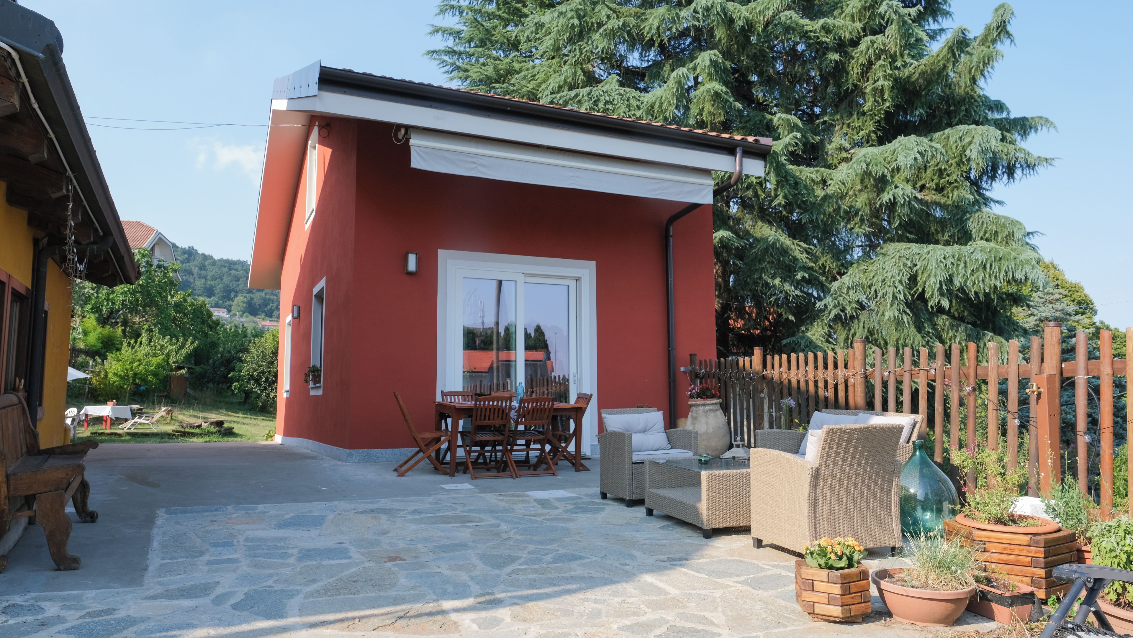 A red building with a patio area, outdoor furniture, and a wooden fence.