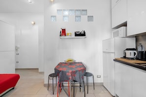 A compact kitchen with a dining table, chairs, a coffee machine, a kettle, and a microwave. - Apartment 'La Perla Del Colosseo' with Wi-Fi and Air Conditioning (Roma)