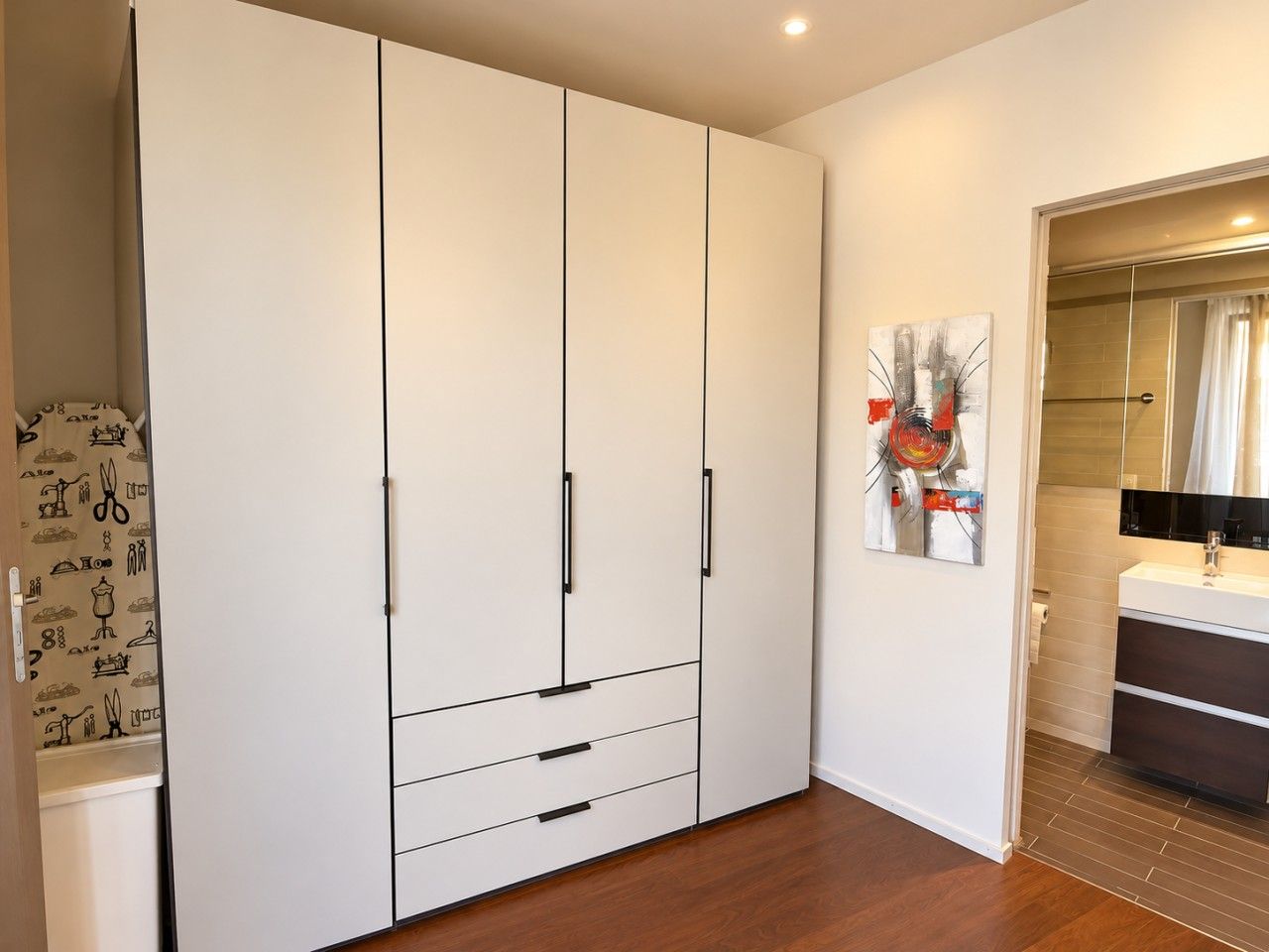 Quarto moderno com um guarda-roupa espaçoso, banheiro com espelho e piso de madeira.