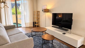 Uma sala de estar moderna com um sofá, duas mesas redondas, uma TV e uma estante.