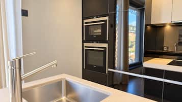A modern kitchen with a stainless steel sink, double ovens, and black cabinetry.