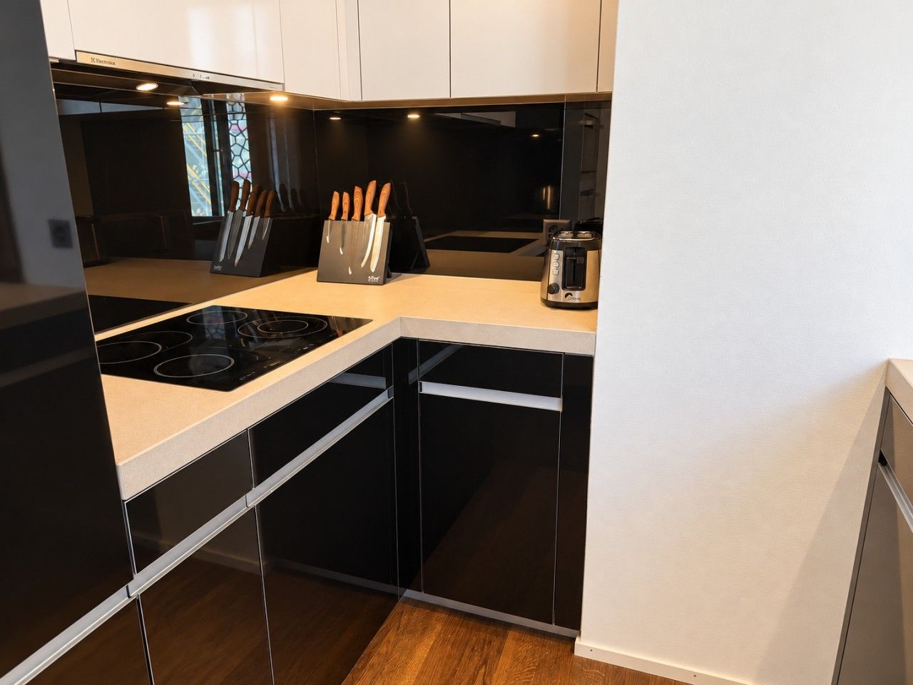 A modern kitchen with black cabinets, a white countertop, and a built-in stove.