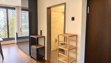 A modern interior with a wooden floor, a black shelving unit, a wooden rack, and a door leading to a bathroom.