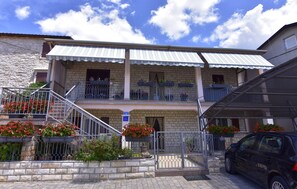 A two-story building with a balcony on the second floor, a staircase leading to the entrance, and a car parked in the driveway. - Charming Apartment in Murine Near Umag (Umag)