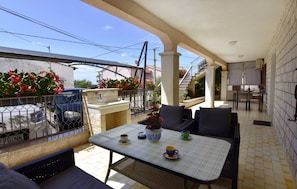 An outdoor patio with a table and chairs, a small fountain, and a view of the street. - Charming Apartment in Murine Near Umag (Umag)