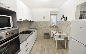 Une cuisine compacte avec des meubles blancs, un four à micro-ondes, une cuisinière et un réfrigérateur.