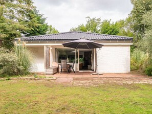 Ein Haus mit überdachter Terrasse, Essbereich und Garten.