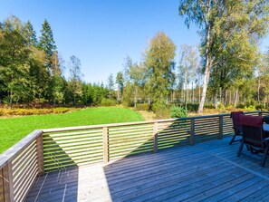 Eine Holzterrasse mit Blick auf eine Wiese und Bäume.