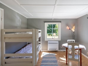 Ein Zimmer mit Etagenbetten, einem Fenster mit Blick, einem Tisch und einem Stuhl sowie einer Klimaanlage.
