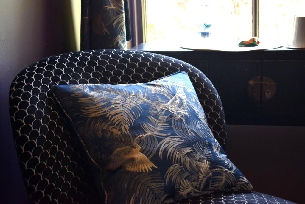 A chair with a patterned cushion and a window in the background.