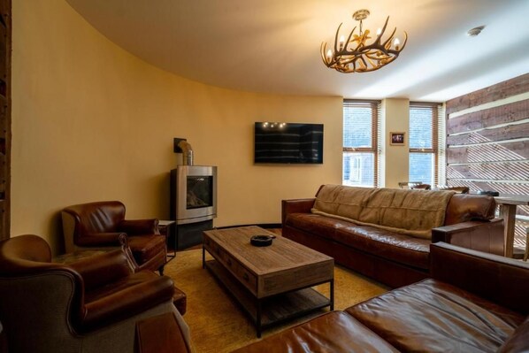 A living room with leather furniture, a fireplace, a television, and a patterned wall.