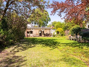 A house with a covered patio, a lawn, and a garden with various plants. - Villa in Bergen With Swimming Pool (Bergen)